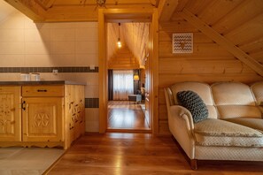Een houten interieur met een keuken, een bank en een gang die leidt naar een woonruimte.