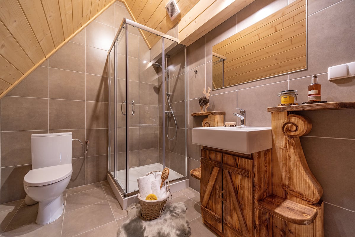 A bathroom with a shower, toilet, and wooden vanity.