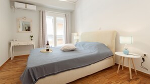 A bedroom with a bed, bedside table, lamp, and a small desk with a mirror. - Cozy Flat in hip Koukaki (Athens)