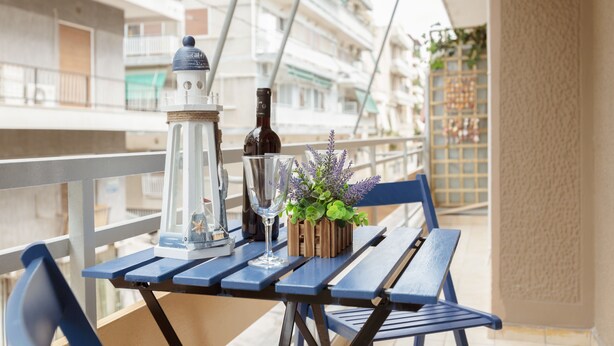 A balcony with a table set with a lantern, a bottle, and a potted plant. - Cozy Flat in hip Koukaki (Athens)