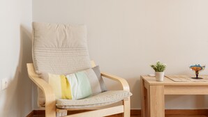 A chair with a cushion, a small table with a plant and a glass bowl, and a framed picture on the wall. - Cozy Flat in hip Koukaki (Athens)