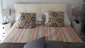 A bedroom with a bed, two bedside tables, a nightstand, a framed floral artwork on the wall, and a patterned bedspread. - Domus Del Corso Spagna (Rome)