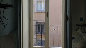 A room with a sliding glass door leading to an outdoor balcony, a chair, and a bed with a patterned bedspread. - Domus Del Corso Spagna (Rome)