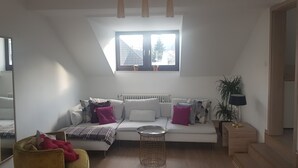 A modern living room with a white sofa, a small round table, and a window with a view of trees. - Boutique-Hotel 'Altes Rathaus' (Lahnstein)