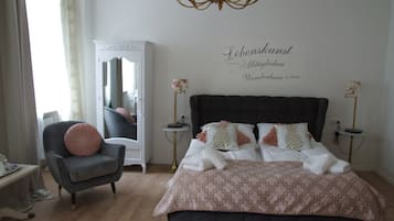 Quarto com uma cama grande, uma cadeira, um guarda-roupa e um candelabro.