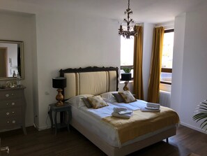 Une chambre à coucher bien rangée, avec un lit, une table de chevet, une lampe et un lustre suspendu.