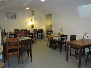 Un espace repas avec des meubles en bois, notamment des tables et des chaises, et un luminaire suspendu.