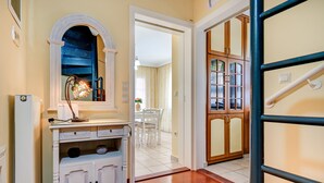 Un couloir avec une armoire blanche, un miroir et une porte donnant sur un coin repas.