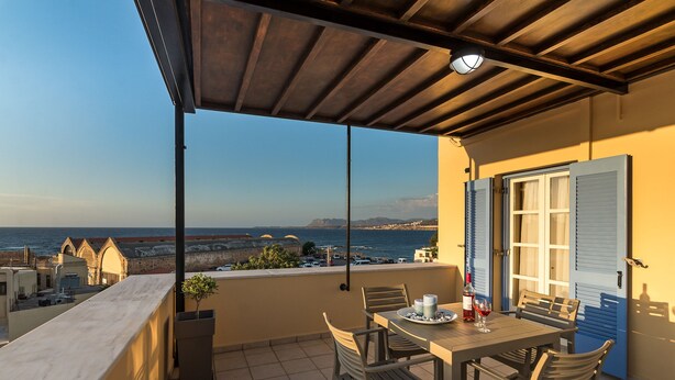 Un balcon avec une table et des chaises, offrant une vue sur la côte.