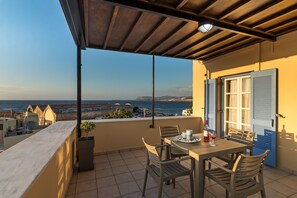 Un balcon avec une table et des chaises, offrant une vue sur la côte.