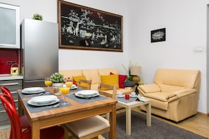 A modern living room with a dining area, a sofa, a chair, and a table set for two.