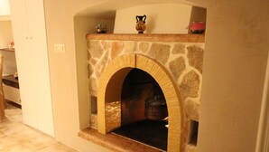 A stone fireplace with a wooden mantel, a small shelf above it, and a tiled floor. - Suite del Vico NEW OPENING! (Alberobello)