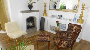 A living room with a fireplace, a white armchair, a leopard print armchair, and a matching ottoman. - Historisches Wirtshaus an der Lahn (Lahnstein)