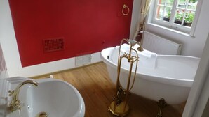 A bathroom with a white bathtub, a gold pedestal sink, and a red wall. - Historisches Wirtshaus an der Lahn (Lahnstein)