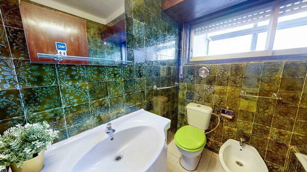 A bathroom with a bathtub, toilet, and sink, featuring green patterned tiles and a wooden cabinet. - Panoramic View Saldanha Guesthouse (Lisbon)