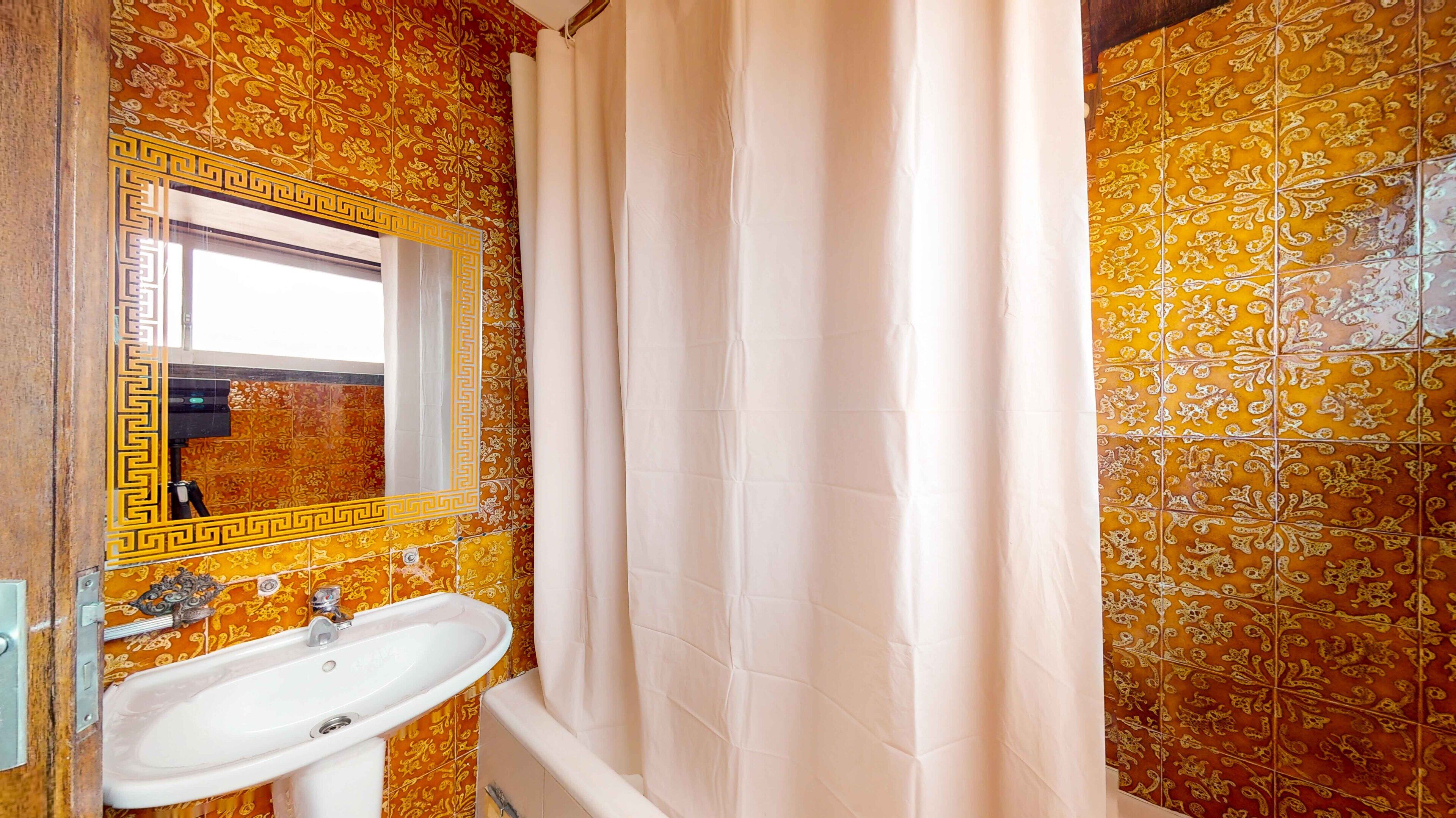 A bathroom with a sink, mirror, and shower curtain.