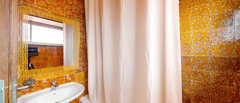 A bathroom with a sink, mirror, and shower curtain.