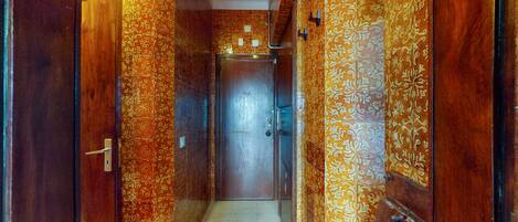 A narrow hallway with ornate patterned walls and a wooden door at the end.