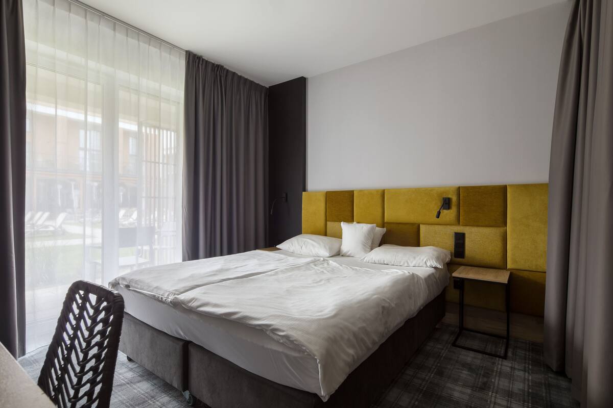 A hotel room with a large bed, a small desk, and a chair.