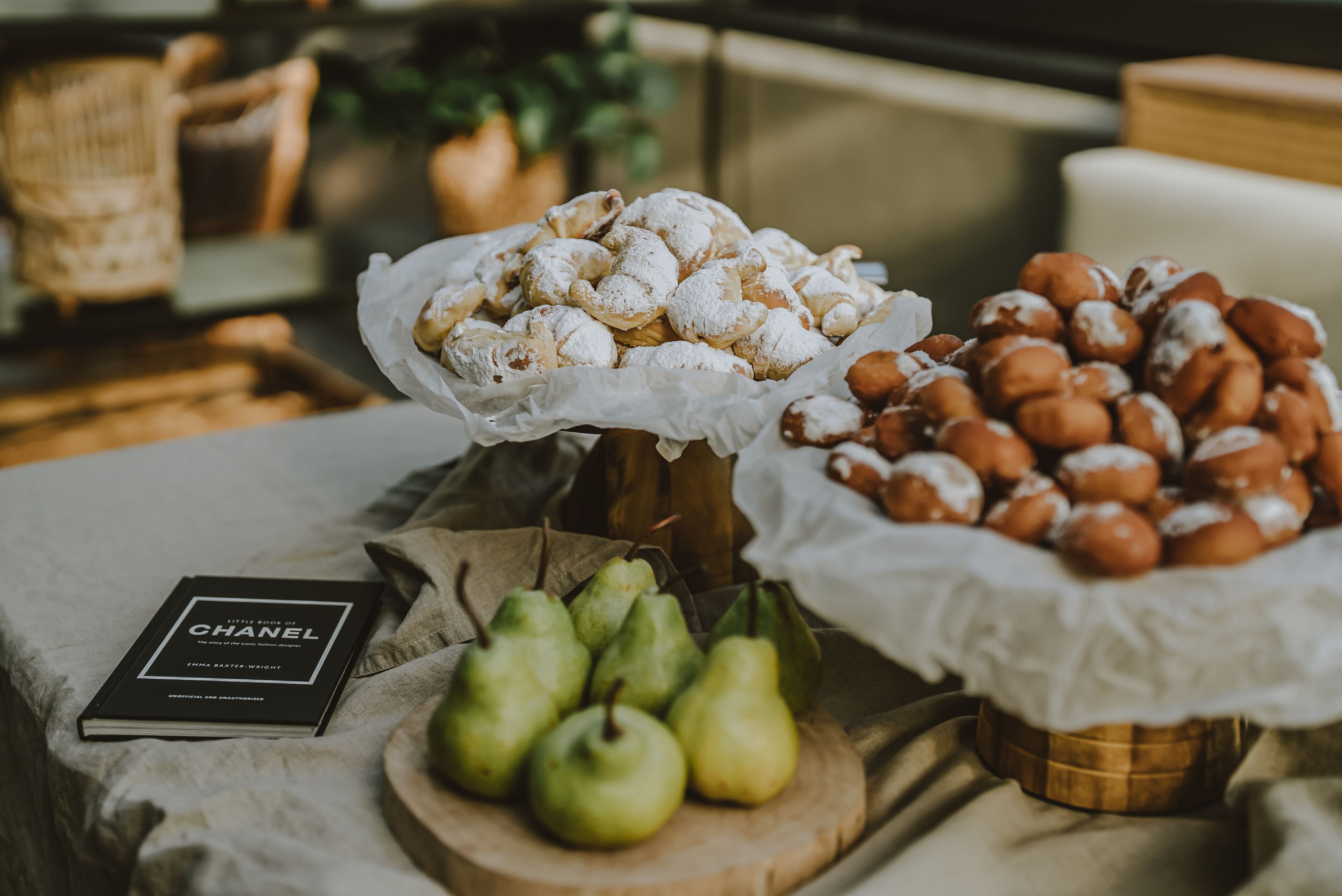 A table with pastries, pears, and a book titled "Little King & I Chanel".