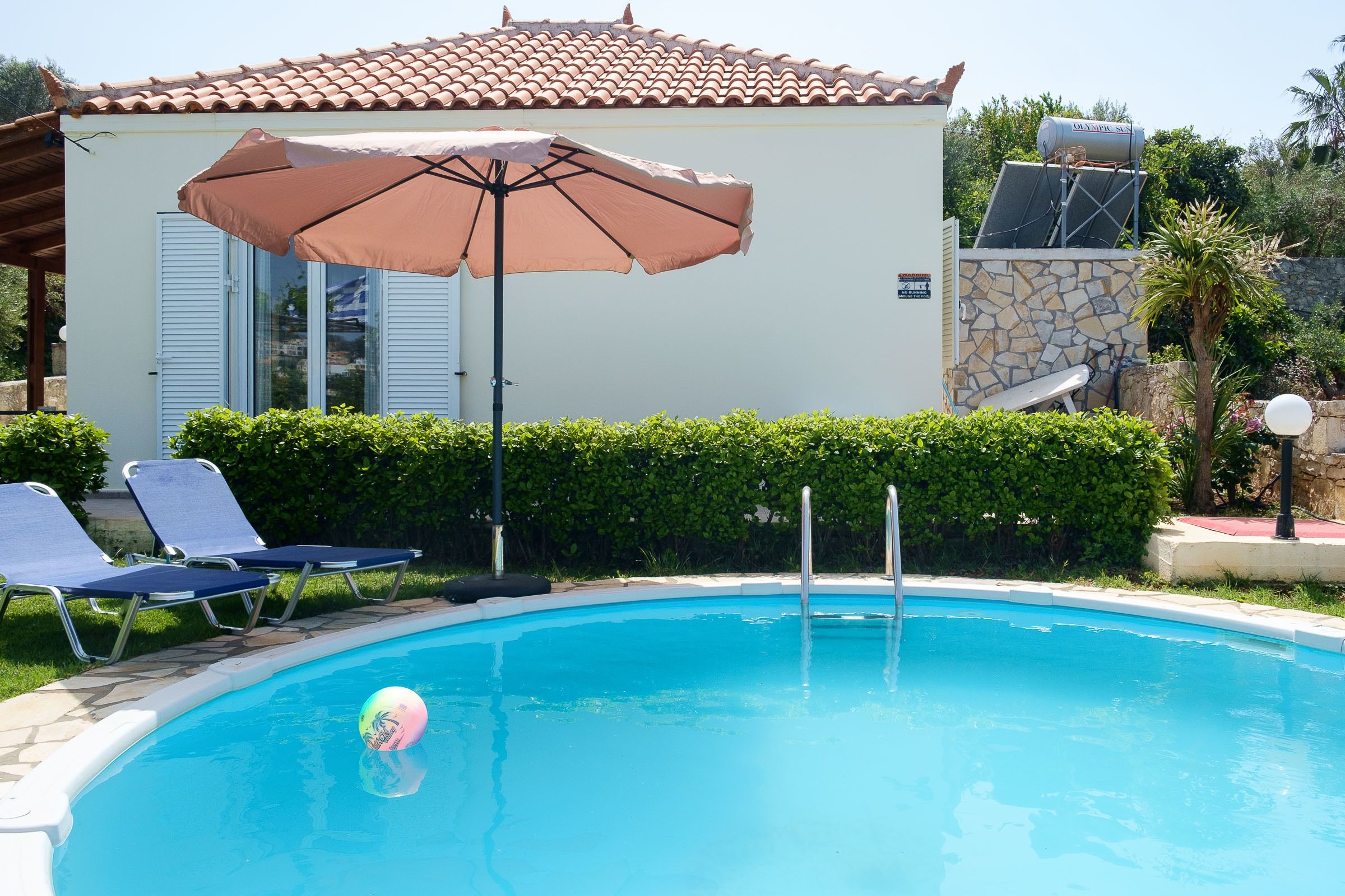 Una piscina con sillones de descanso y una sombrilla grande.