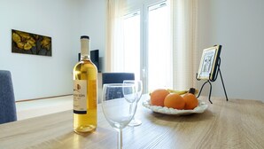 Una mesa con una botella de vino, dos copas y un plato de naranjas.