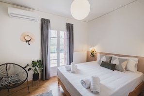 Una camera da letto ordinata con un letto, una sedia, una pianta in vaso e una finestra con tende.