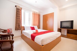 Une chambre bien rangée, avec un lit, une télévision et une armoire en bois.
