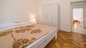 A bedroom with a bed, a wardrobe, and a nightstand with a lamp. - Apartment Anica (Malinska-Dubasnica)