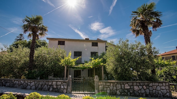 A two-story building with a stone wall and a metal gate in front. - Apartment Anica (Malinska-Dubasnica)