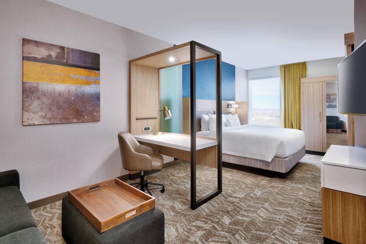 Ein Hotelzimmer mit Bett, Schreibtisch, Stuhl und einem großen Fenster.