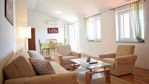 A living room with beige sofas, a glass coffee table, and a dining area in the background. - Apartment Blue Dream 1 & 2 (Malinska-Dubasnica)