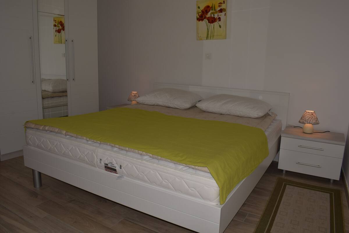 Ein Schlafzimmer mit Bett, Nachttischen, einem Spiegel und einem Wandbild.