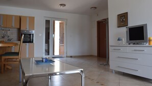 A modern kitchen with a dining area, including a table, chairs, and a TV on a cabinet. - Apartment Blue Dream 1 & 2 (Malinska-Dubasnica)