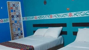Ein Zimmer mit zwei Einzelbetten, einem Deckenventilator und einer mit Fliesen verkleideten Wand.