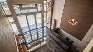 A modern hotel lobby with a reception desk, seating area, and a view of the street. - One Nk Apartments (Santiago)
