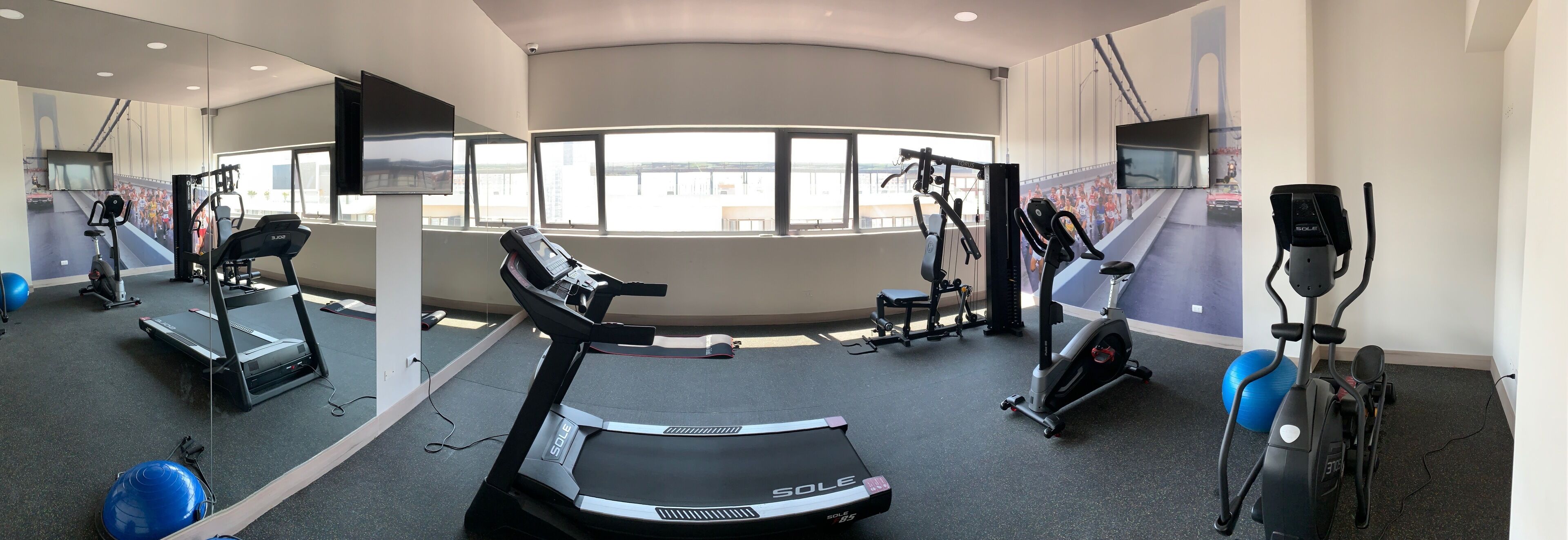 Een fitnessruimte met loopbanden, hometrainers en krachttrainingsapparatuur.