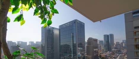 A high-rise building with a view of a cityscape, including other tall buildings and a busy street below.