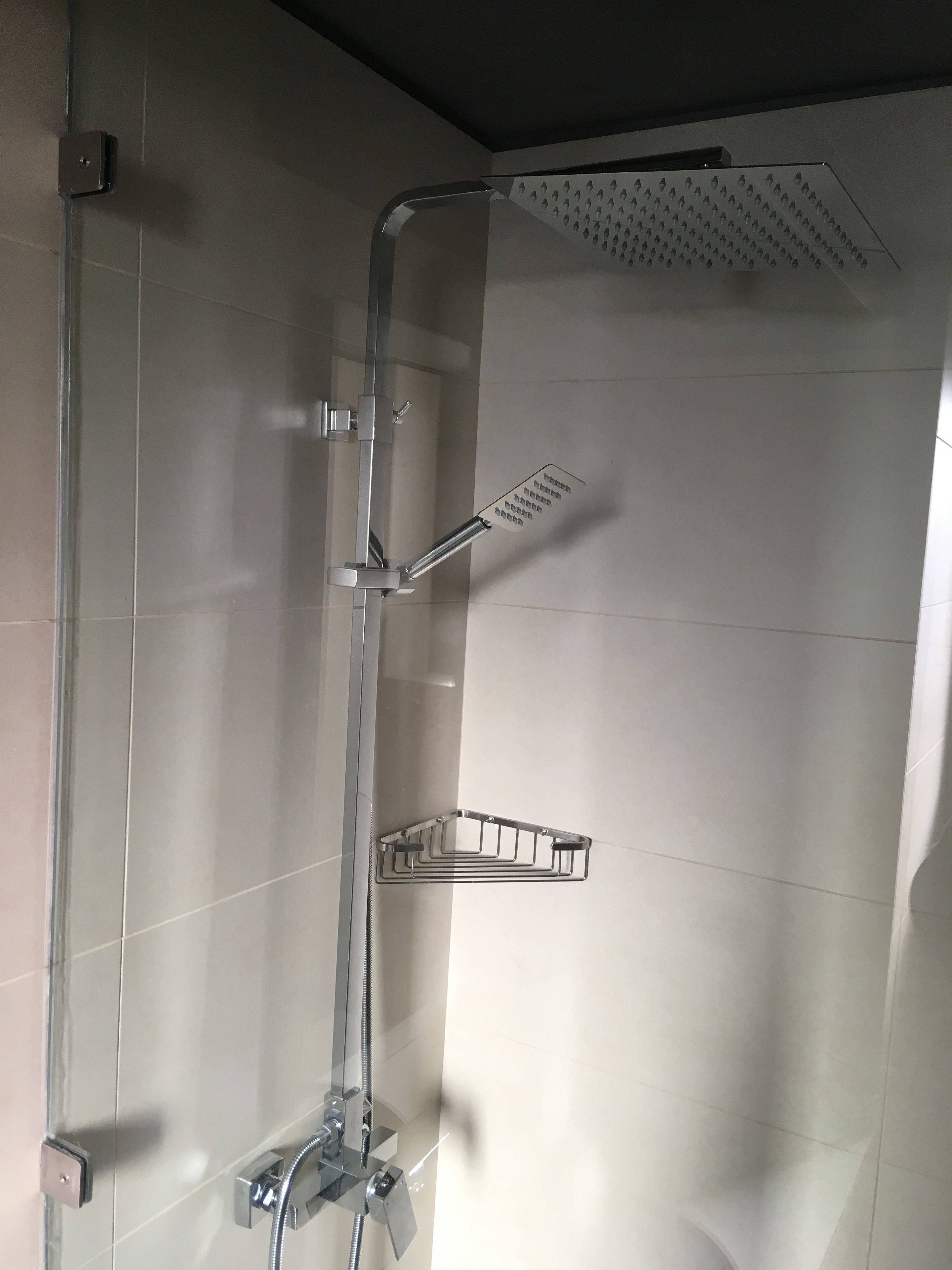 A shower with a handheld showerhead and a wall-mounted rain showerhead.