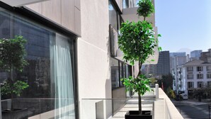 A modern building with large windows and a potted tree on the balcony. - One Nk Apartments (Santiago)