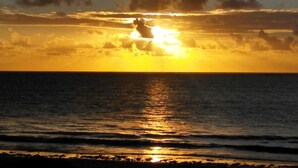 Un coucher de soleil sur l’océan, avec des nuages dans le ciel.