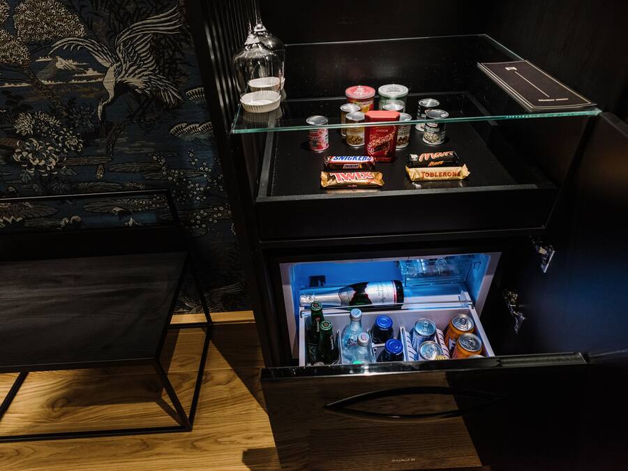 A minibar with snacks and beverages, a glass shelf, and a decorative wall.