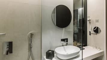 A modern bathroom with a white sink, a round mirror, and a glass-enclosed shower area.
