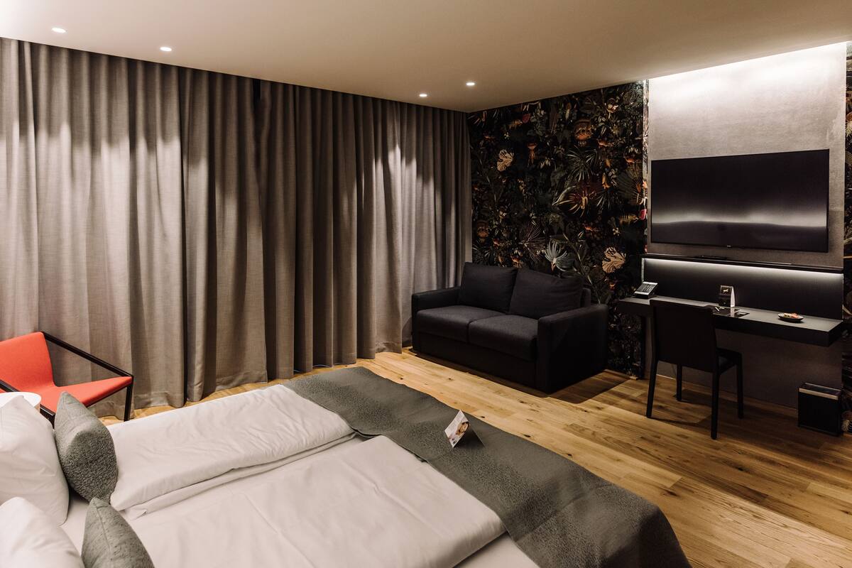 Ein modernes Hotelzimmer mit Bett, Schreibtisch, Fernseher und einer Sitzecke.