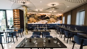 Un restaurante moderno con suelo de mármol, asientos tapizados en azul y una cava de vinos visible a través de una pared de cristal.
