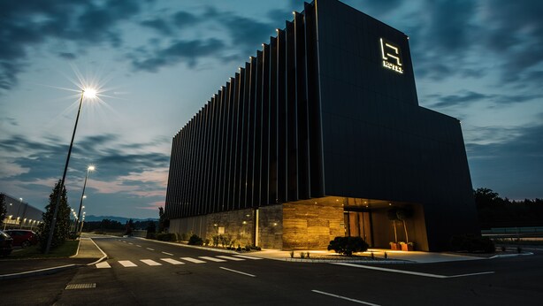 Un edificio moderno con un logotipo destacado en la fachada, una entrada bien iluminada y un cielo despejado al fondo.