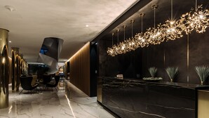 Un moderno vestíbulo con un mostrador de recepción de mármol, sillas elegantes y un candelabro único.