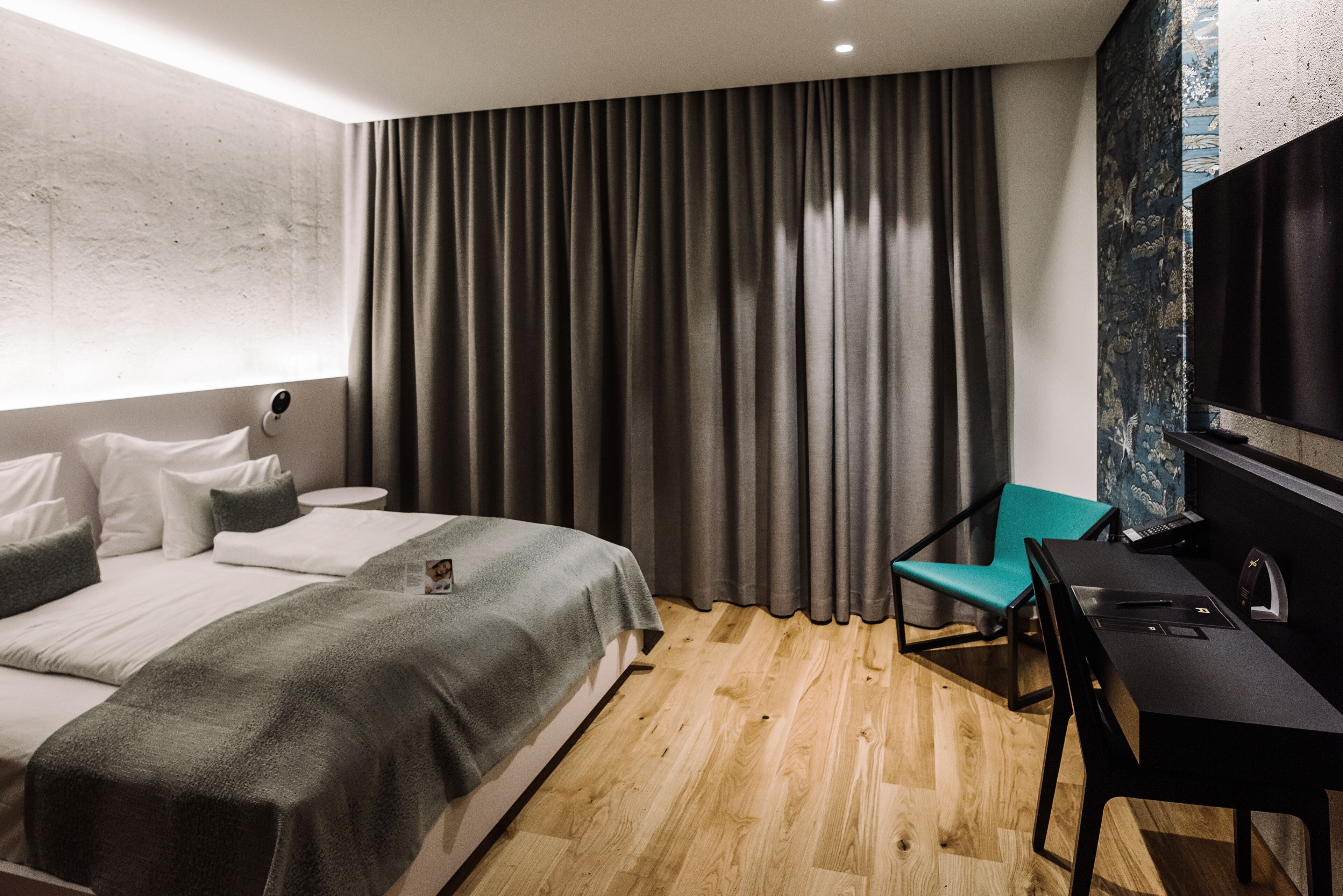 Una habitación de hotel moderna con una cama grande, un escritorio con una computadora portátil, una silla y un televisor.