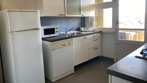Une cuisine avec des meubles blancs, un four à micro-ondes et un évier.