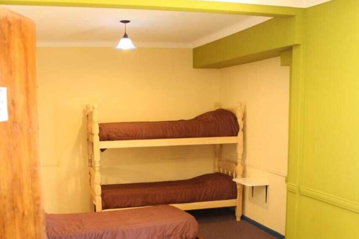A dormitory room with two bunk beds, a small table, and a door.
